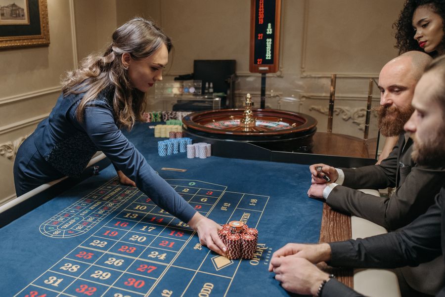 Meja roulette dengan dealer dan pemain di kasino