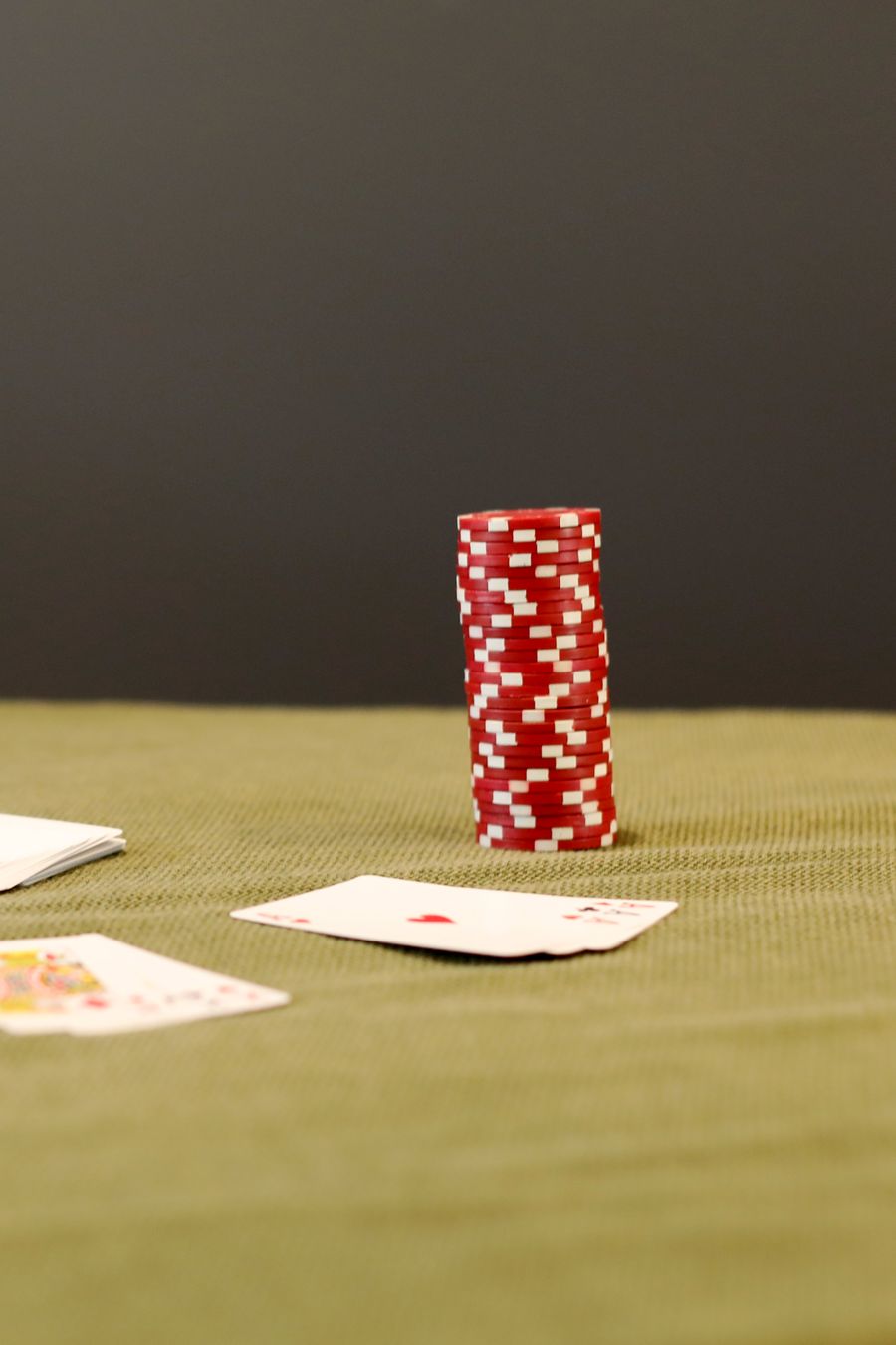 Chip poker merah dan kartu remi di atas meja hijau